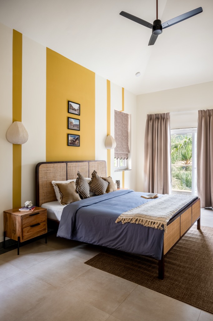 Casa Aurea bedroom with mustard paint bands and a cane bed